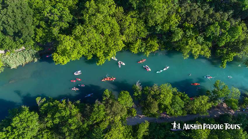 Aerial view of kayaks, canoes, and stand-up paddleboards (SUPs) on Barton Creek, a feeder spring flowing into Lady Bird Lake, Austin, Texas.